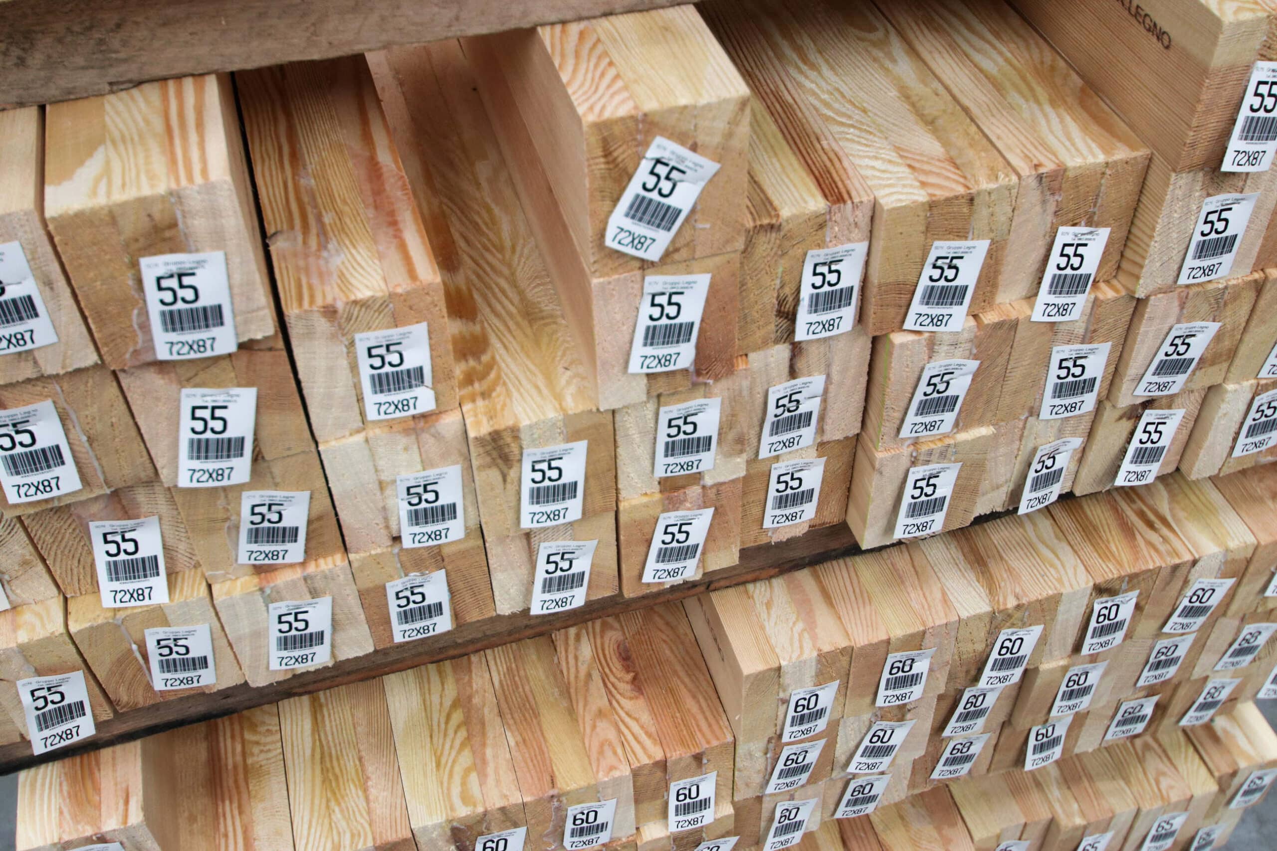 Travi di legno impilate con etichette numeriche.