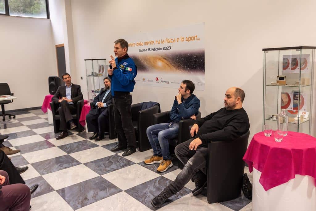 Uomo in piedi parla a un pubblico seduto.